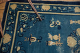 Antique Peking rug: denim blue field with antique ivory symbolic urns and patterned border.