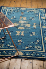 Antique Peking rug's detailed denim blue field, ivory floral cross-sections, urns, and Taoist motifs.