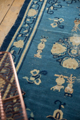 Antique Peking rug's blue field, ivory urn and floral Taoist motifs.