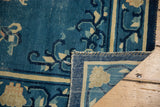 Antique Chinese Peking rug's folded corner, revealing hand-knotted foundation and worn pile.