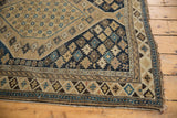 Antique Caucasian Shirvan rug corner showing geometric motifs, worn side cord. Colors: sand, dark navy, sky blue.