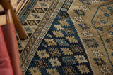 Geometric border and starburst patterns of an antique Shirvan rug in navy, sand, and sky blue.