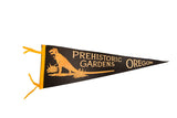 Vintage Prehistoric Gardens Oregon black felt pennant with orange T-Rex graphic and yellow ties.