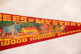 Vintage red felt pennant showing 'Trees of Mystery' text, Babe the Bull, and panoramic graphic.