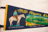 Navy felt pennant showing Will Rogers on Soapsuds, ranch home, yellow rope lettering.