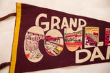 Vintage graphics of the Grand Coulee Dam depicted inside the letters of the maroon felt pennant.