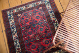 Overhead view of the vintage Engelas rug with its red Herati pattern on a wood floor.