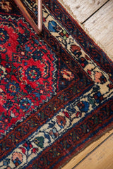 Close-up of the corner spandrel and ivory vine border on a vintage Persian Engelas rug mat.