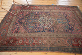 Aged geometric borders and blush, blue, red floral motifs on an antique Kurdish Bijar rug.
