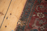 Detailed view of the antique Kurdish Bijar rug's worn edge, showing tatter and exposed foundation.