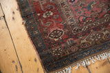 Tattered edge and fringe of antique Kurdish Bijar rug, displaying geometric flower motifs in muted red and blue.