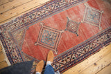 Geometric medallion, patterned border, blush red abrash field, and tattered fringe on antique Malayer rug.