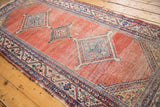 Antique Malayer runner detail: blue geometric medallion with arrowed finials, blush red abrash field, and visible wear.