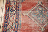 Antique Malayer rug showing striated red abrash field and geometric blue, ivory medallion with arrowed finials, reflecting wear.