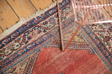 Antique Malayer runner showcasing a worn pale red field, intricate blue border motifs, and tattered fringe.