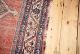 Tattered side edge of an antique Malayer runner with red, blue, and ivory borders.