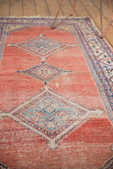 Blush cinnabar red field showing localized wear around a geometric blue Malayer medallion.