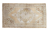 Distressed Oushak rug with octagonal medallion in soft beige, muted green, and brown.