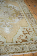 Beige, green, and brown scalloped spandrel and border on distressed vintage Oushak rug.