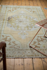 Decorator style distressed Turkish Oushak rug corner, soft green arabesque spandrel and fringe.