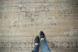 Distressed Oushak rug's low pile and even wear, featuring muted beige and charcoal patterns.