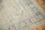 Distressed Oushak rug corner, showcasing even wear, exposed foundation, and fringe.