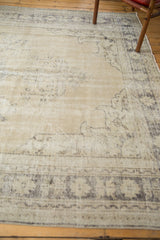 Textural distressed vintage Oushak carpet showing worn beige field and faded charcoal border.