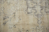 Distressed Oushak rug texture showing worn beige pile and visible knot heads.