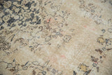 Vintage distressed Sivas carpet detail: worn beige field, charcoal vinery, visible foundation, and blush tones.