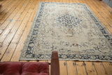 Distressed vintage Sivas carpet detail: ornate charcoal blue vinery, time-softened beige, blush rose.
