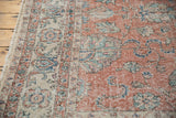 Distressed vintage Sparta carpet, close-up of worn blush field with ivory border and scrolling vinery.