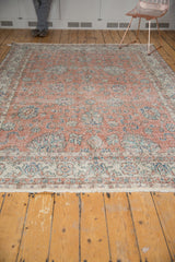 Distressed vintage Sparta carpet with faded dusty rose, blue, and ivory palmette vinery.