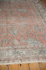 Blush field of a distressed vintage Sparta carpet, blue and green vinery, faint foundation showing.