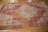 Distressed pile with scrolling rococo design and corner spandrels of Oushak rug.