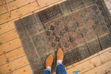 Distressed Belouch rug with staggered geometric guls in copper, blush, sky blue, and brown.
