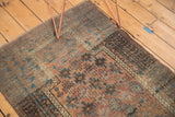 Distressed Belouch rug with geometric guls, showing muted copper and sky blue tones.