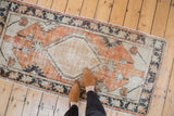 Distressed Oushak rug runner with faded brick red and antique ivory diamond medallion.