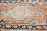 Distressed Oushak runner's worn dusty brick red field, ivory corner, and floral motif.