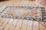 Distressed Oushak rug's scalloped diamond medallion, antique ivory, dusty brick red, and charcoal tones.