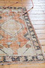Distressed Oushak runner corner: dusty brick red field, ivory floral spandrel, original selvage.