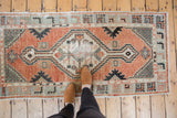 Distressed vintage Oushak runner featuring cinnabar, seafoam green, and beige medallion end detail.