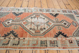 Distressed Oushak runner: stepped diamond medallion in cinnabar red and beige tones.