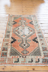 Distressed vintage Oushak rug corner showing geometric borders and worn cinnabar, pistachio green pile.