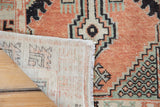 Textured cinnabar red and seafoam green distressed Oushak rug pile with visible beige foundation and fringe.