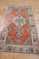Distressed Oushak runner with a pale brick red field and beige diamond medallion.