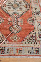 Vintage distressed Oushak rug with brick red field, beige spandrel, and slate blue geometric border.