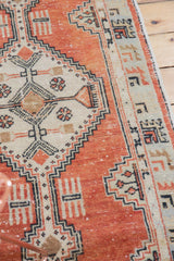 Distressed pale brick red field and beige stepped geometric motifs of a vintage Oushak rug.