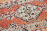 Distressed pale brick red Oushak runner with stepped diamond medallion and plant motifs.