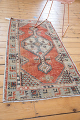 Distressed vintage Oushak runner corner with brick red, beige germinating plant motifs and fringe.