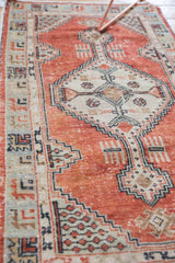 Stepped diamond medallion and distressed brick red pile of a vintage Oushak runner.